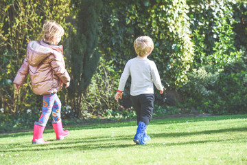 Fototapeta premium Siblings playing together a boy and girl are playing outside in a garden during daytime