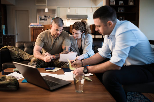 Military couple reviewing paperwork with financial advisor at home