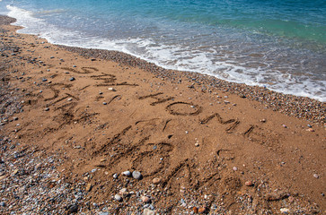 Text written on the sand STAY HOME during coronavirus quarantine on the beach in suburb in South Athens, Greece - spring 2020.
