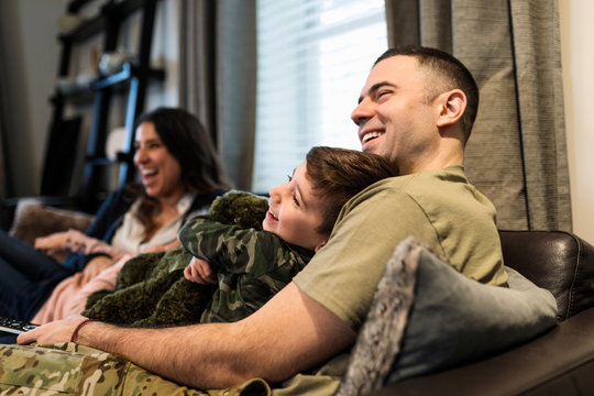 Happy military family relaxing and watching TV on sofa