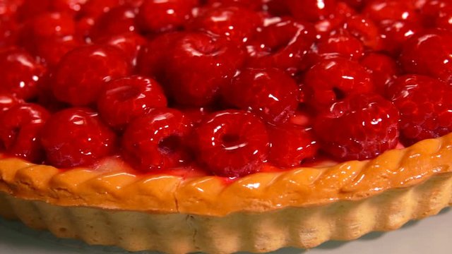 Camera movement on the side of delicious Fresh raspberry pie covered with jelly
