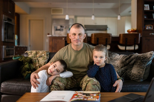 Portrait soldier father and daughters on sofa