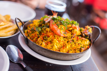 Traditional paella with rice and seafood on a plate on the table. Lifestyle