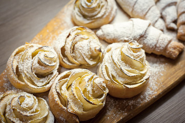 Close up of delicious croissants and pastries with apples, on a wooden Board in a cafe