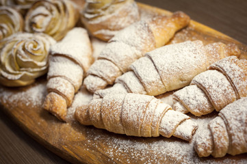 Close up of delicious croissants and pastries with apples, on a wooden Board in a cafe