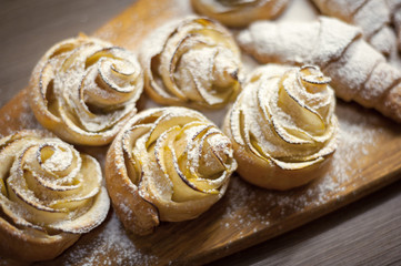 Close up of delicious croissants and pastries with apples, on a wooden Board in a cafe