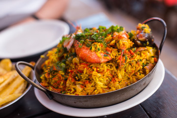 Traditional paella with rice and seafood on a plate on the table. Lifestyle