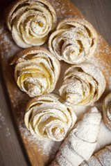 Close up of delicious croissants and pastries with apples, on a wooden Board in a cafe