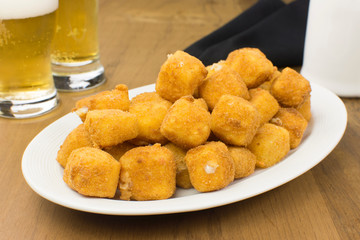 Traditional Brazilian pub food provolone cheese in breadcrumbs called provolone a milanesa in a wood table