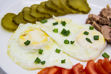 Delicious fresh tuna with eggs, tomatoes, cucmbers with green onion at the morning. Healthy and diet breakfast with tuna, eggs and vegetables on the white plate against white background