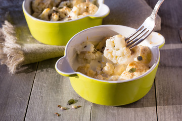 Baked cauliflower with cream on wooden table
