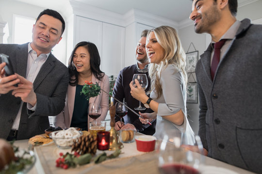 Friends laughing at content on smartphone at Christmas party