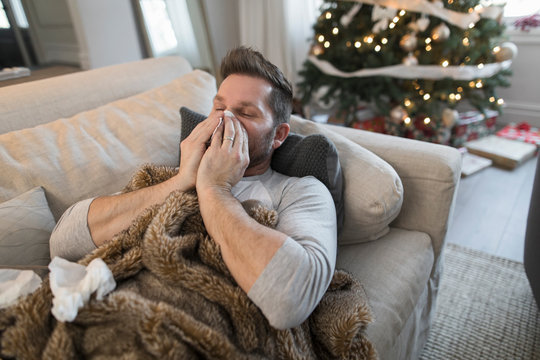 Man with common cold at Christmas blowing nose