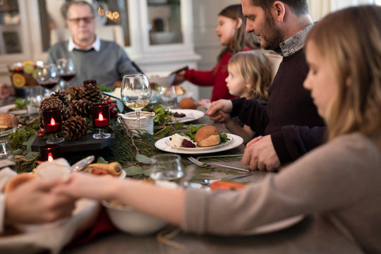 Extended family giving thanks before having Christmas dinner