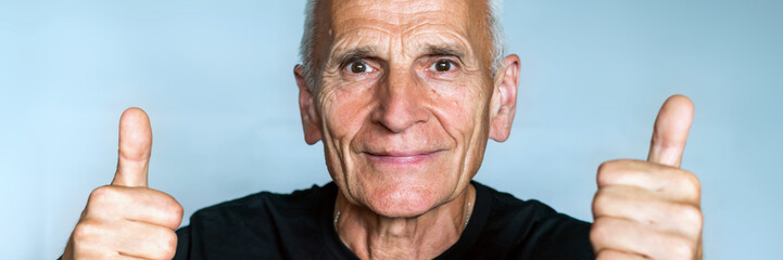 Happy positive elderly man in black T-shirt thumb up on two hands