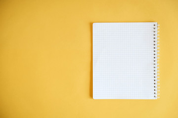 Blank notebook for writing on yellow background. Top view. Copy, empty space for text