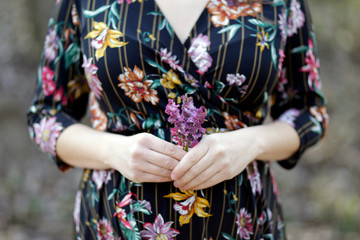 Spring pregnancy photoshoot. Detail on pregnancy belly. Woman holding flowers. 