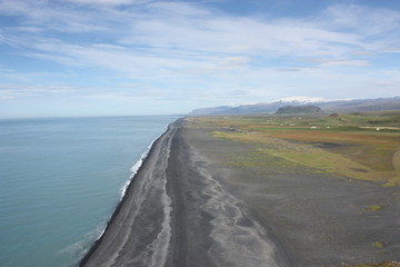Fototapeta premium Wide black sand beach seen from Dyrholaey promontory, Iceland with glacier at the background - Large plage de sable noir vue depuis un promontoire en Islande avec glacier en arrière plan