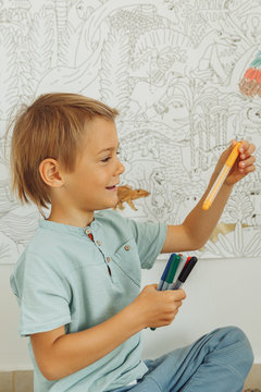 baby boy draws on the wall with red felt-tip pens
