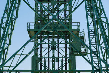 Front view partly detail of industrial  tower with green painted steel truss structure, lift and...