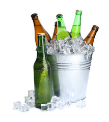 Metal bucket with bottles of beer and ice cubes isolated on white © New Africa