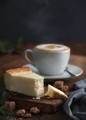 cutaway cheesecake, with mint, pieces of cane sugar, cappuccino on a wooden board