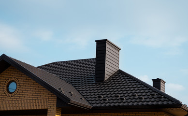 Brown metal tile roof. Roof metal sheets. Modern types of roofing materials. Roof of the house, metal roof tile against the blue sky. Building.