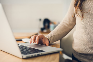 Fototapeta premium Young woman working on laptop computer at home due to corona virus pandemic. Working remotely concept.