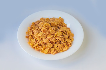 Their flakes are poured a lot. The plate is white. Close-up. The background is not uniform