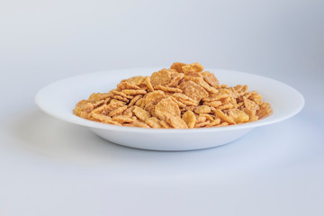 Their flakes are poured a lot. The plate is white. Close-up. The background is not uniform