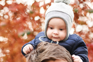 a small son sits on the shoulders of a young father