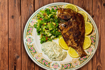 fried fish with fresh salad and lemon.