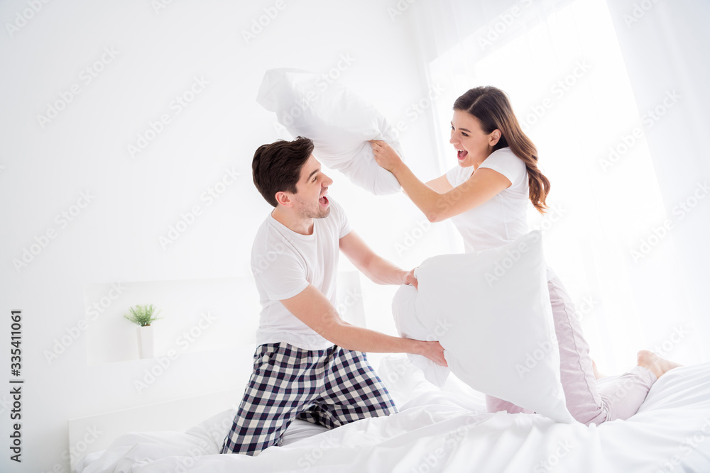 Poster Photo of attractive lady cheer handsome guy married couple in love playing pillow fight sheets bed enjoy weekend saturday morning good excited mood wear pajama room indoors