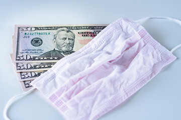 Top view on USD american dollar banknotes money on the table with protective medicine surgical mask over pandemic and epidemic influence on the economy and recession concept