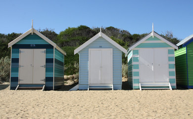 Fototapeta na wymiar Row of blue beach cabins in Brighton Beach with Hokusaï Wave 