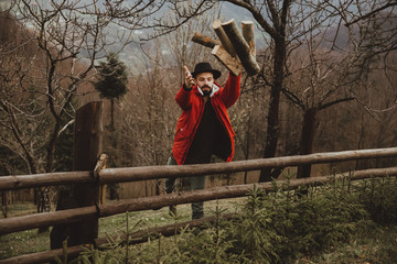 Hipster with beard,  Man in hat and warm jacket chopping and preparing firewood for picnic
