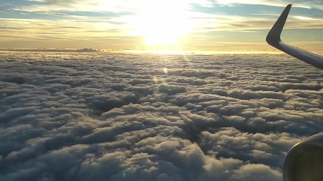 Traveling above the clouds on a commercial airliner in the morning shortly after sunrise.