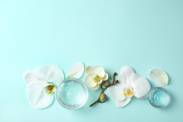 Flat lay composition with cosmetic gel and beautiful flowers on light blue background. Space for text