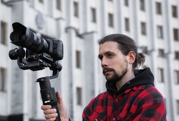 Young Professional videographer holding professional camera on 3-axis gimbal stabilizer. Pro...
