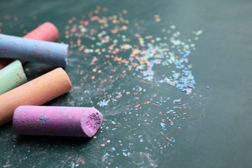 Pieces of color chalk on greenboard, closeup. Space for text
