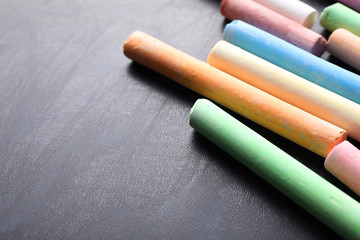 Pieces of color chalk on blackboard, space for text