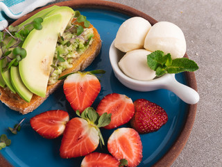 toast with guacamole, avocado, strawberries mozzarella cheese on a plate