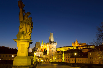 Fototapeta na wymiar Night colorful Prague gothic Castle with St. Nicholas' Cathedral and Bridge Tower from Charles Bridge with its baroque Statues without People at the time of Coronavirus, Czech Republic