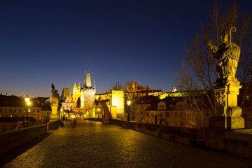 Naklejka premium Night colorful Prague gothic Castle with St. Nicholas' Cathedral and Bridge Tower from Charles Bridge with its baroque Statues without People at the time of Coronavirus, Czech Republic
