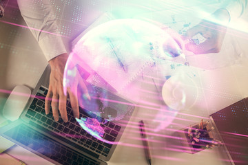 Double exposure of man's hands typing over computer keyboard and tech theme hologram drawing. Top view. Technology concept.