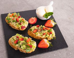 toast with guacamole, avocado, strawberries. mozzarella cheese. healthy eating
