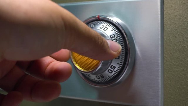 Man hand Opening old safe combination lock turning dials.
