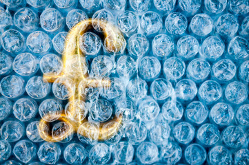 Fragile golden British pound symbol protected under a layer of plastic bubble wrap
