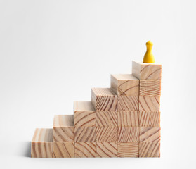 Yellow game piece on top of stairs against white background. Career promotion concept