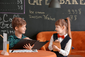 Cute little waiter serving client in restaurant
